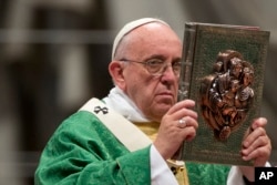 Pope Francis raises the book of the Gospels as he celebrates the opening Mass of the Synod of bishops, in St. Peter's Basilica at the Vatican, Oct. 4, 2015.