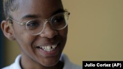 Tinazsha Johnson, 15, talks about her project on rice water during the science fair a New Song Community Learning Center in Baltimore, where she is learning to cope with her sorrow and stress. (AP Photo/Julio Cortez)