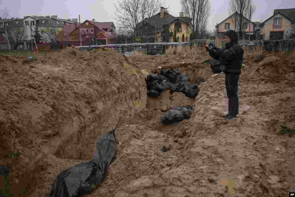 A journalist takes video of a mass grave in Bucha, on the outskirts of Kyiv, Ukraine.
