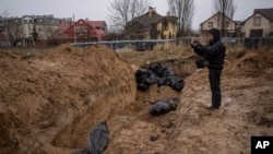 Seorang jurnalis mendokumentasikan kuburan massal di Bucha, pinggiran Kyiv, Ukraina, Minggu (3/4). 