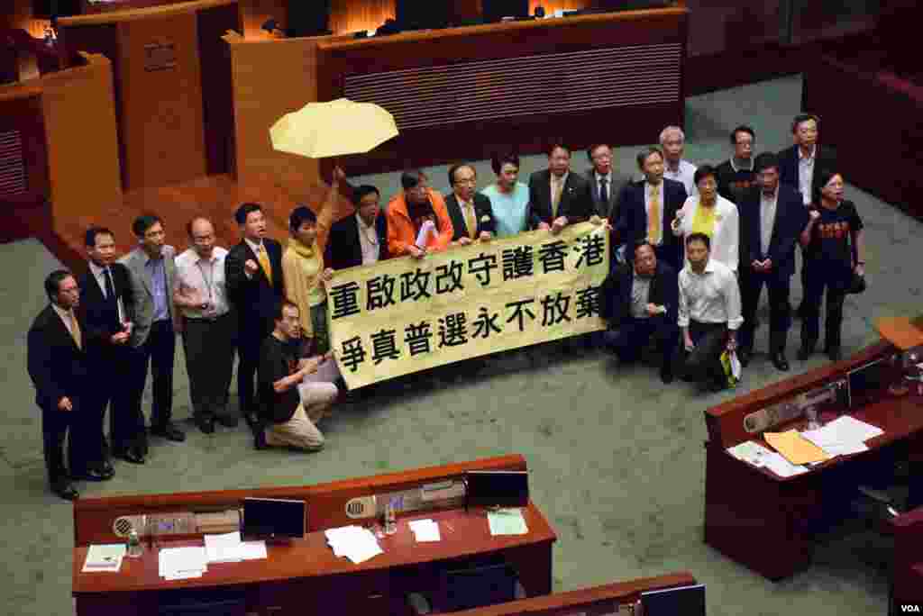 20多位泛民主派立法會議員在港府政改方案被否決後，到會議廳內主席台前展示標語。（美國之音 湯惠芸攝)