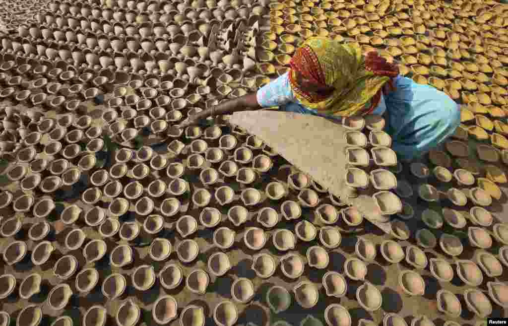인도 북부 찬디가르시에서 한 여성이 힌두 축제에 쓰기 위해 흙으로 빚은 등잔을 건조시키고 있다.