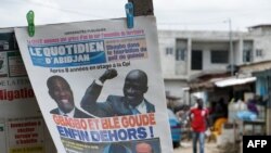 FILE - A newspaper reading "Gbagbo and Ble Goude finally out!" is seen in Abidjan's popular Yopougon district, a day after the International Criminal Court freed former Ivory Coast president Laurent Gbagbo and his aide Charles Ble Goude, Feb. 2, 2019.