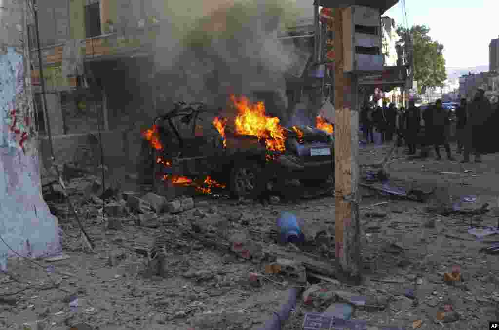 This photo provided by the Syrian Civil Defense White Helmets, which has been authenticated based on its contents and other AP reporting, shows Syrians around a burning car hit by a shell, in the town of Afrin, north of Aleppo.&nbsp;The rocket attack on Afrin, controlled by Turkey-backed opposition fighters, killed several civilians and wounded over a dozen people, Syrian rescuers and a war monitor said.