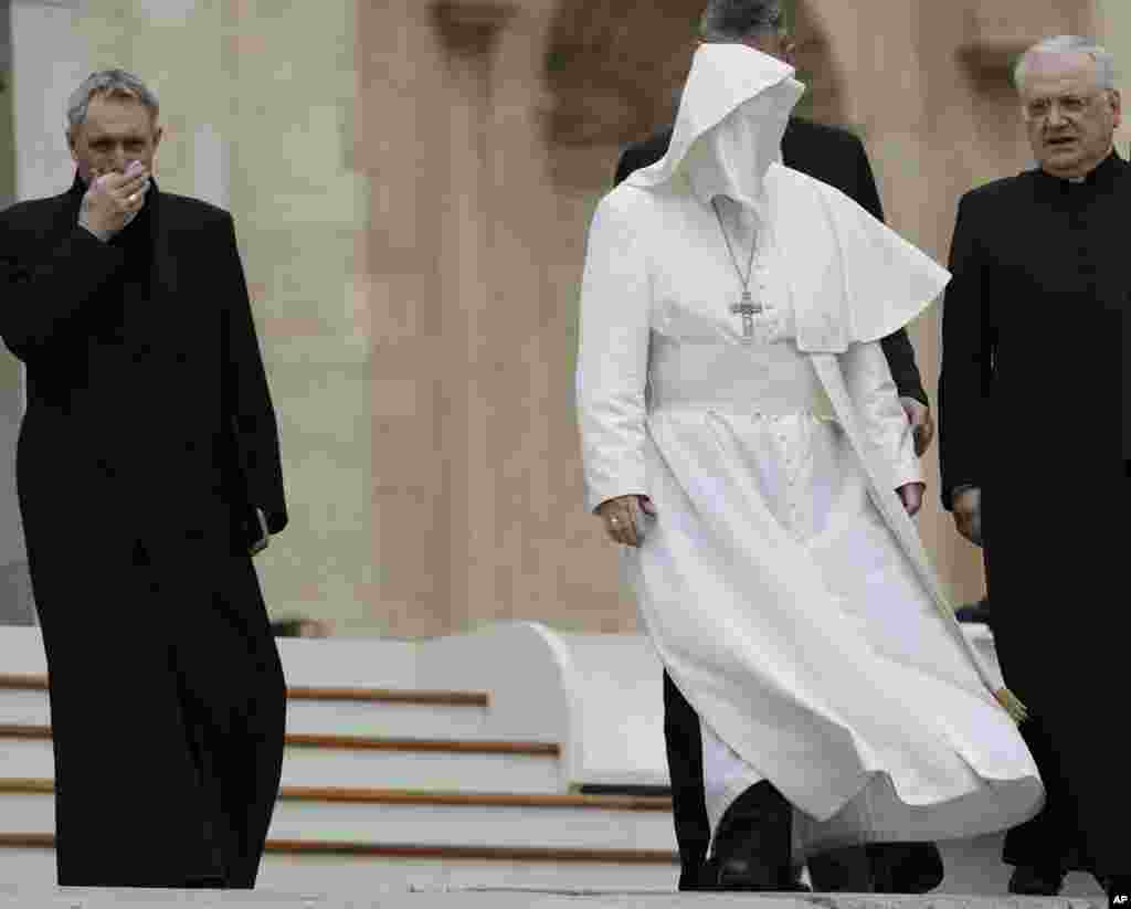 A gust of wind messes up Pope Francis' cape as he leaves with Monsignor Leonardo Sapienza and Archbishop Georg Ganswein at the end of his weekly general audience in St. Peter Square at the Vatican.