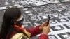 Una mujer toma una fotografía de pancartas con las imágenes de víctima del conflicto colombiano colocadas en el pavimento durante una manifestación frente a la sede de la Unión Europea en Bogotá, el 9 de abril de 2021.