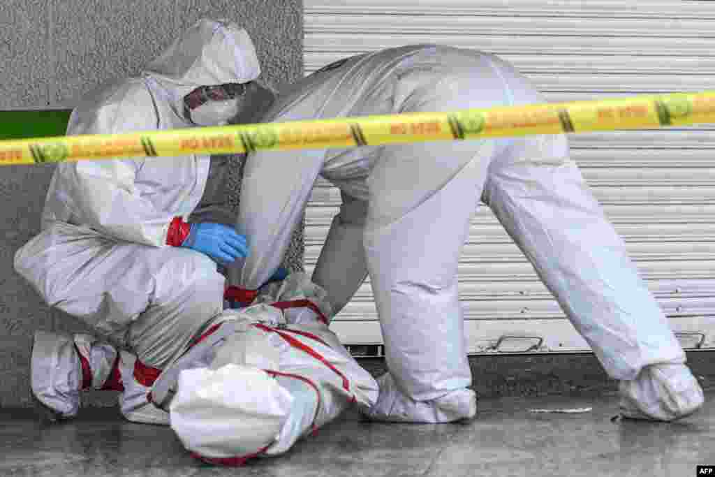 Police officers wearing protective suits remove the body of a man who died in the street amid the coronavirus pandemic, in Medellin, Colombia, May 6, 2020,.