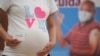Seorang ibu hamil memperlihatkan kartu vaksinasinya di Bogota, 23 Juli 2021. (Raul ARBOLEDA / AFP)