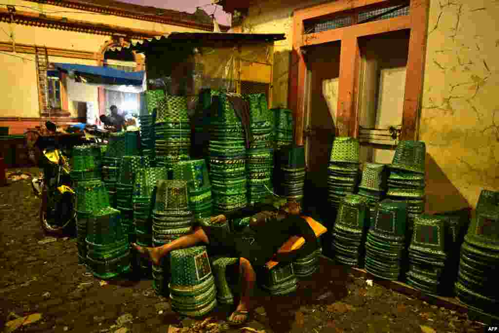 A worker rests on baskets used to carry acai fruit after working all night at the Ver-o-Peso wholesale market in Belem, Amazonia region, Para State, Brazil. The Ver-o-Peso market is considered one of the oldest public markets in the country and was elected one of the wonders of the state of Pará and one of the Seven Wonders of Brazil.