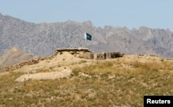 FILE - A Pakistani flag flies on top of a Pakistani check post at the Goshta district of Nangarhar province, where Afghanistan shares borders with Pakistan, May 2, 2013.