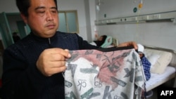 Man displays a blood stained coat in a hospital after his son was stabbed during a knife attack that took place on December 14, 2012 at a primary school in Guangshan county, central China's Henan province. 
