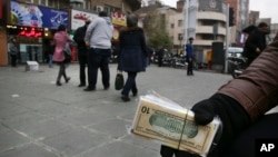 지난해 12월 이란 테헤란 시내에서 환전상이 이란 지폐와 미국 달러 지폐 뭉치를 손에 들고 있다.