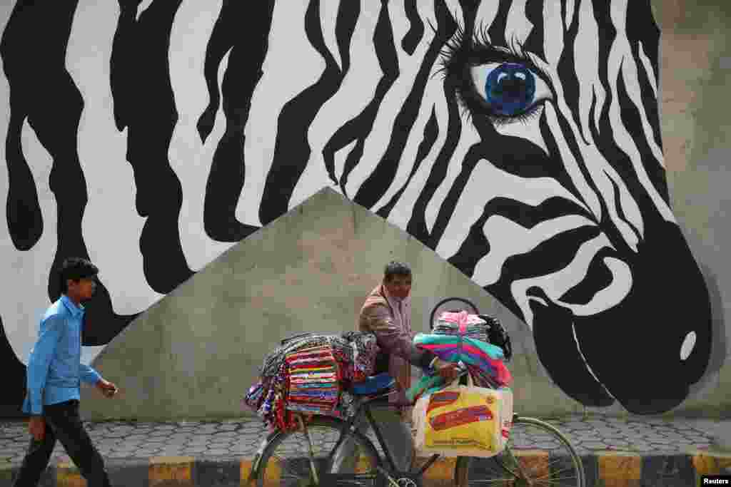 A vendor walks past graffiti along the streets of Lalitpur, Nepal.