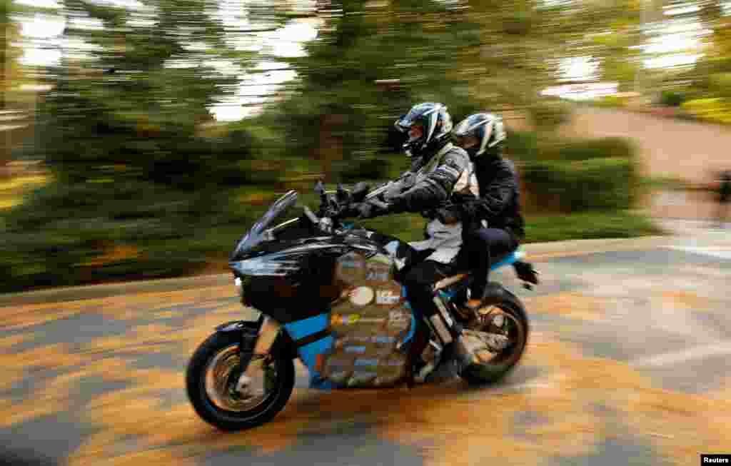 Bram Van Diggelen, (L), the demonstration driver of the Storm Eindhoven, the world&#39;s first long distance electric motorcycle, takes a member of the media for a ride at the Royal Netherlands Embassy in Washington, D.C.