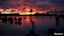 A villager wades through a small lagoon, which at high-tide laps at the base of homes, near the village of Tangintebu on South Tarawa in the central Pacific island nation of Kiribati, which consists of a chain of 33 atolls and islands that stand just met