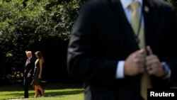 El presidente Donald Trump y la primera dama Melania Trump caminan hacia el helicóptero que los llevará al retiro presidencial de Camp David, mientras un agente del Servicio Secreto resguarda el área en la Casa Blanca. Sep. 8 de 2017.