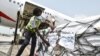 FILE - A woman attaches COVAX stickers to a shipment of AstraZeneca Covid-19 vaccine from a plane at Felix Houphouet Boigny airport of Abidjan on Feb. 26, 2021.