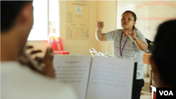 Flautist Phon Chanleakhena, a senior at the Royal University of Fine Arts, conducts members of the Phnom Penh Marching Band during a rehearsal at Kolab Primary School in Phnom Penh on September 16, 2018. (Rithy Odom/VOA Khmer)