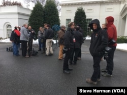 Members of a White House press pool waiting outside the West Wing on a chilly day.
