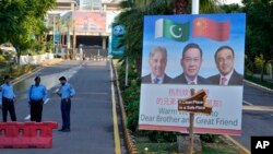 Police officers stand guard next to a welcome billboard with portraits of China's Premier Li Qiang, center, Pakistan's Prime Minister Shehbaz Sharif and President Asif Ali Zardari, ahead of the Shanghai Cooperation Organization summit in Islamabad, Pakistan, Oct. 13, 2024.