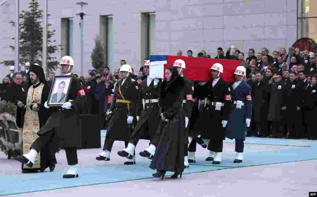 Members of a Turkish forces honor guard carry the Russian flag-draped coffin of late Russian Ambassador to Turkey Andrei Karlov and a picture of him during a ceremonial farewell with full state honors on the tarmac of Ankara&#39;s Esenboga Airport.