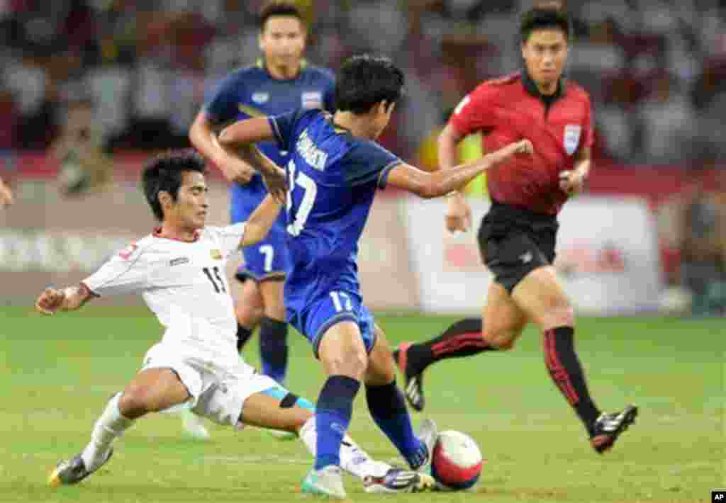 Hein Thiha Zaw of Myanmar, left, is tackled by Tanaboon Kesarat of Thailand, centre, during the soccer final at the SEA Games in Singapore, Monday, June 15, 2015. (AP Photo/Joseph Nair)