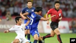 Hein Thiha Zaw dari Myanmar, kiri, dijegal oleh Tanaboon Kesarat dari Thailand, tengah, pada pertandingan final sepakbola SEA Games di Singapura, Senin (15/6).