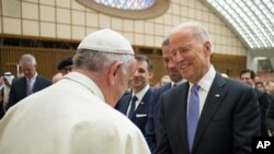 FILE - On April 29, 2016, Pope Francis shakes hands with then-U.S. Vice President Joe Biden in the Pope Paul VI hall at the Vatican.