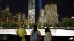 ara pengunjung ke Memorial Nasional 11 September menonton instalasi seni yang terdiri dari 88 lampu sebagai bagian dari peringatan serangan 11 September 2001 (8/9). (AP/Mark Lennihan)