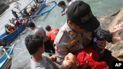 Polisi menggendong seorang anak yang tidak sadarkan diri setelah perahu yang membawa para pencari suaka tenggelam di Cianjur, Jawa Barat. (Foto: Dok)