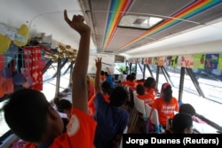 A migrant child raises his hand a bus converted into a classroom by California's 'Yes We Can' organization, in Tijuana, Mexico August 2, 2019