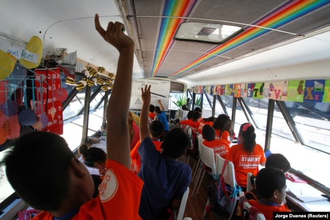 A migrant child raises his hand a bus converted into a classroom by California's 'Yes We Can' organization, in Tijuana, Mexico August 2, 2019