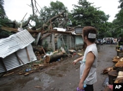 Injured resident Arnel Castillo looks at the damage to his home caused by a fallen tree from Typhoon Koppu in suburban Quezon city, north of Manila, Philippines, Oct. 19, 2015.