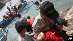 Seorang polisi menggendong seorang anak perempuan yang pingsan setelah kapal pencari suaka yang ditumpanginya tenggelam di lepas pantai pulau Jawa di Cianjur, Jawa Barat, Rabu (24/7). Hingga hari ini, jumlah korban dilaporkan telah mencapai 15 orang. 