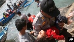 Polisi membawa seorang anak yang pingsan pasca kapal karam di Jawa Barat (24/7).