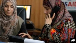 Pakistani lawyer Shandana Naeem, right, listens to a caller with her colleague Nayab Hassan at their office in Peshawar, March 28, 2017. 