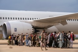 Afghan people who were transported from Afghanistan, walk after disembarking a plane, at the Torrejon military base as part of the evacuation process in Madrid, Aug. 23, 2021.