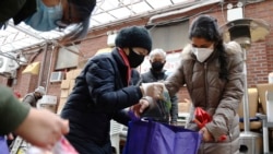 United Sherpa Association treasurer Tshering Sherpa helps college students like Jyoti Rajbanshi, pack free food in bags during the group's weekly food pantry on Friday, January 8, 2021, in Queens, New York. (AP Photo/Jessie Wardarski)