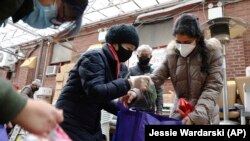 United Sherpa Association treasurer Tshering Sherpa helps college students like Jyoti Rajbanshi, pack free food in bags during the group's weekly food pantry on Friday, January 8, 2021, in Queens, New York. (AP Photo/Jessie Wardarski)