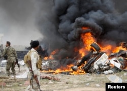 FILE - Shi'ite fighters known as Hashid Shaabi look at smoke from an explosives-laden military vehicle driven by an Islamic State suicide bomber which exploded during an attack on the southern edge of Tikrit.