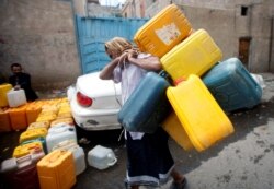 FILE - A man carries jerry cans to fill them with water from a charity tap amid a shortage of drinking water in Sanaa, Yemen, Oct. 11, 2019.