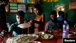 Azimul Hasan, 10, seorang anak laki-laki pengungsi Rohingya, sedang melayani pelanggan di sebuah hotel tempat dia bekerja, di pinggir jalan dekat kamp Palong Khali, Cox's Bazar, Bangladesh, 12 November 2017. (REUTERS/Navesh Chitrakar)