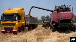 FILE: A combine harvester offloads wheat grain into a truck during a harvest at a farm in Bindura about 88 kilometres north east of the capital Harare, Monday, Oct, 10, 2022.