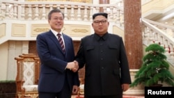 Presiden Korea Selatan, Moon Jae-in berjabat tangan dengan Pemimpin Korea UTara, Kim JOng-un di Pyongyang, Korea Utara, 18 September 2018. 