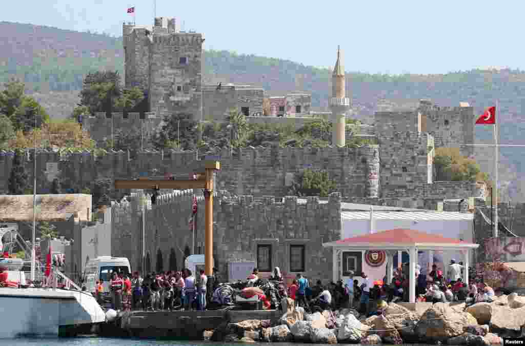 In Turkey, migrants wait at a coast guard station after a failed attempt to sail off for the Greek island of Kos by a dinghy, near the resort town of Bodrum. Twenty-two migrants drowned and 200 more were rescued when a boat capsized in the Aegean Sea off the Turkish coast while trying to reach the Greek island of Kos, the Turkish coastguard said.