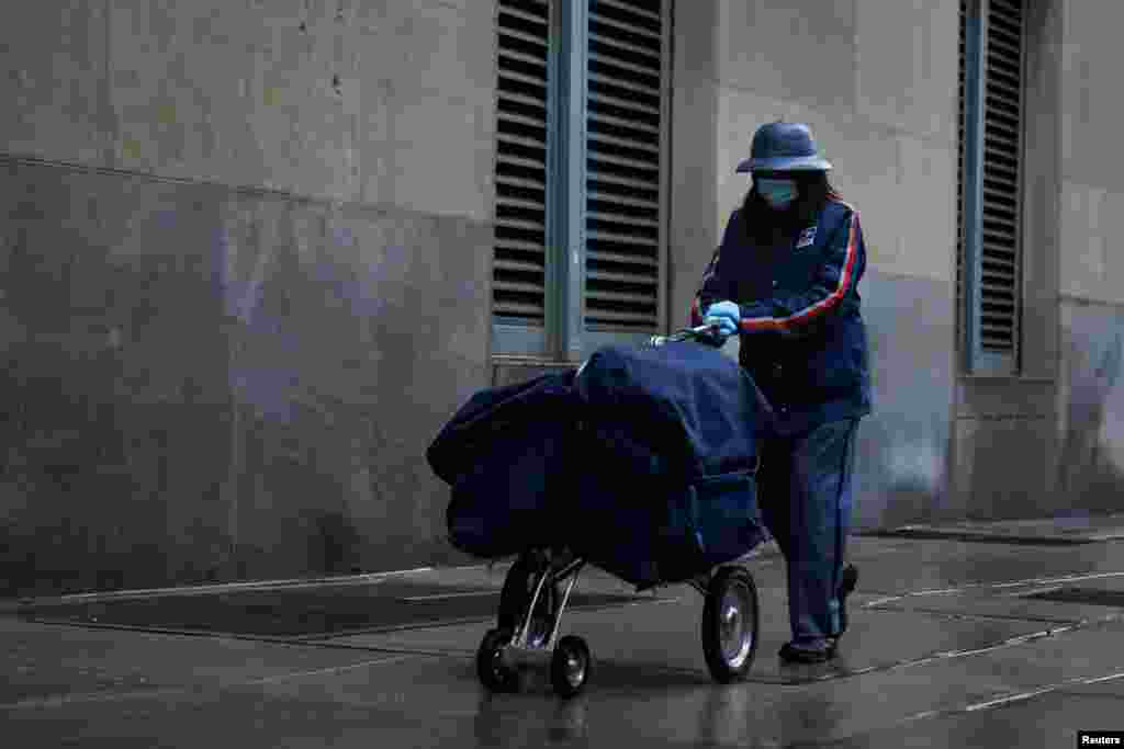 A United States Postal Service (USPS) worker delivers mail in the rain in Manhattan during the outbreak of the coronavirus disease (COVID-19) in New York City, April 13, 2020.