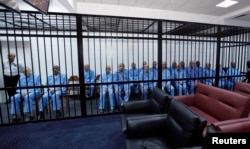 Officials of Muammar Gadhafi's government sit behind bars during a hearing at a courtroom in Tripoli, Libya, April 27, 2014.