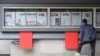 A man reads a newspaper displayed on a street for the public in Seoul on October 21, 2024, with coverage (in left case) on North Korea's decision to deploy thousands of soldiers to Ukraine's front lines.