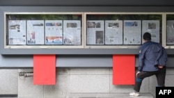 A man reads a newspaper displayed on a street for the public in Seoul on October 21, 2024, with coverage (in left case) on North Korea's decision to deploy thousands of soldiers to Ukraine's front lines.