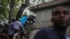 FILE - Journalists climb up a wall to take cover from gunfire, after being shot at by armed gangs at the General Hospital in Port-au-Prince, Haiti, Dec. 24, 2024.